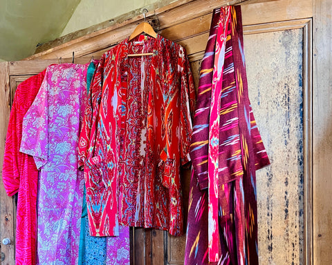Caro London's pink and red printed kimonos in long and short lengths hanging from the top of a door