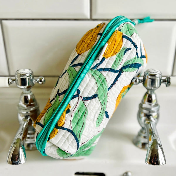 large scale floral print long quilted make up bag leaning on wash basin