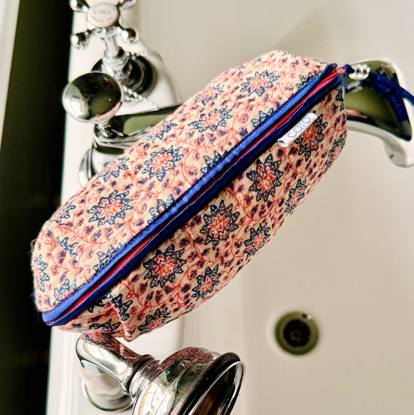 Over view of long, quilted make up bag in peach and blue floral print with dark blue trim