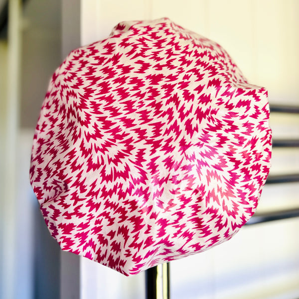 Shower cap with pink and cream splashy abstract print hanging on the wall