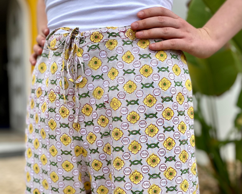 Person wearing a white top and floral-patterned pants with a blurred outdoor background
