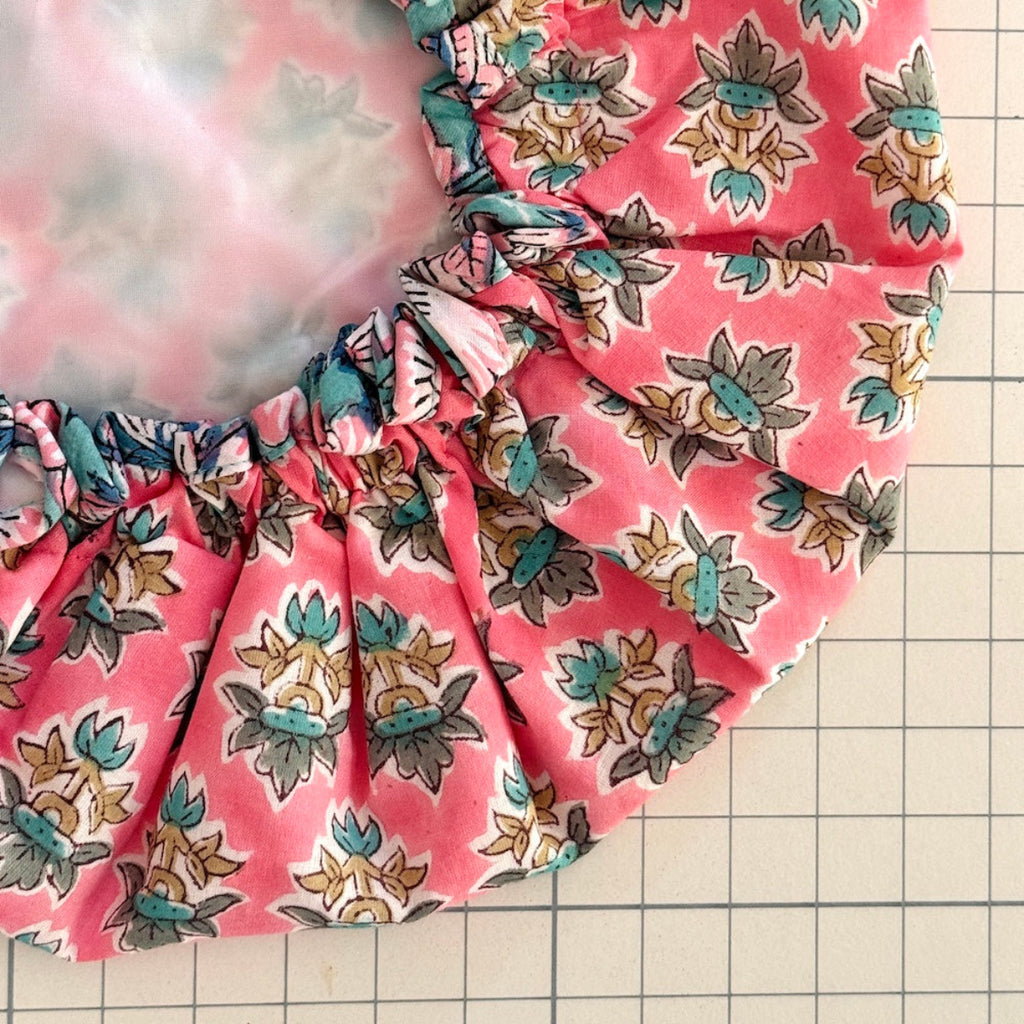 Close up of pink floral print bath hat with white water resistant lining