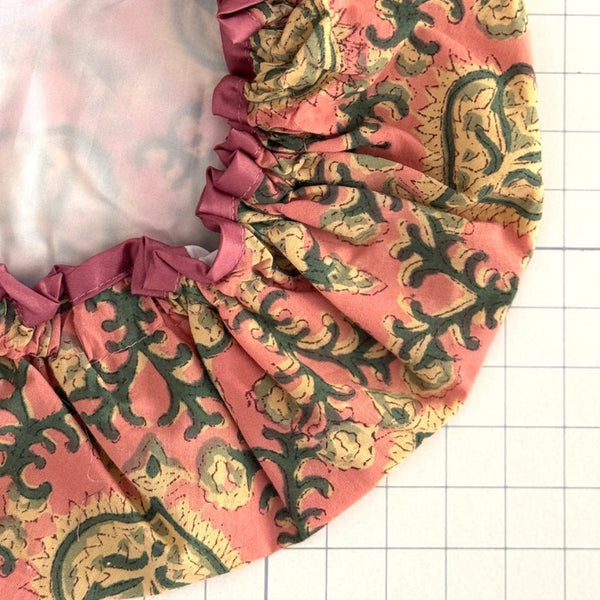 Close up of floral print bath hat in antique pink, cream and green colour palette