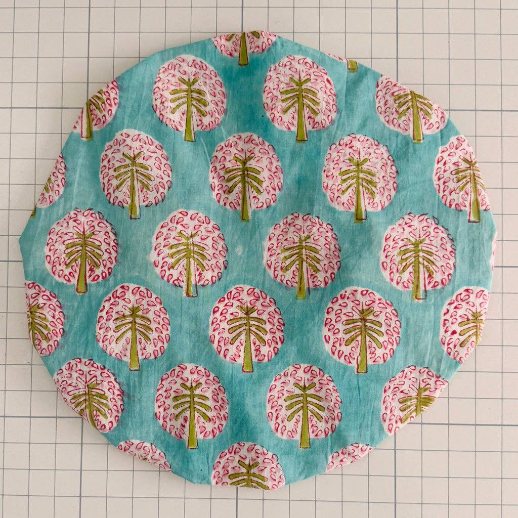 Circular bath hat with a palm tree pattern on a grid background