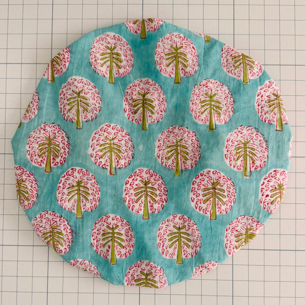 Circular bath hat with a palm tree pattern on a grid background