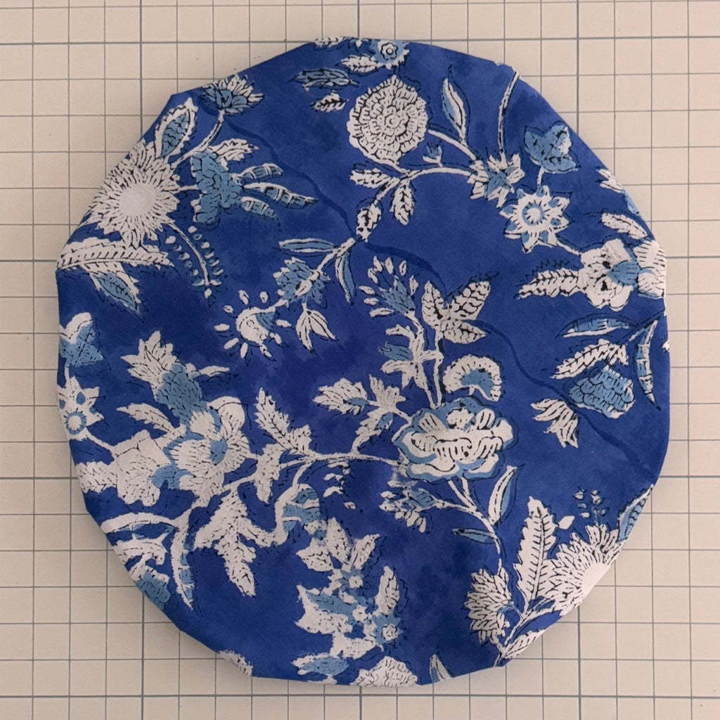 Blue fabric with white floral print bath hat on a grid background