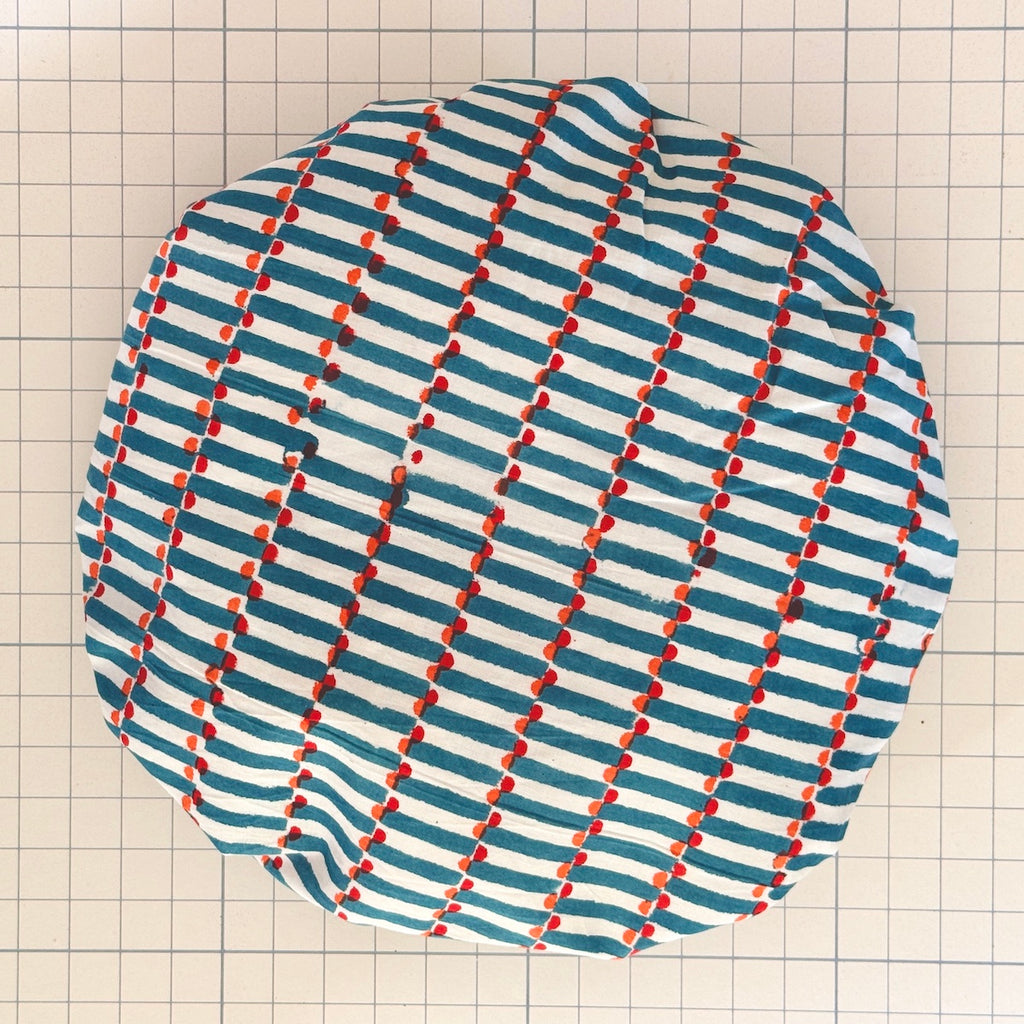 Patterned Bath hat in blue stripes on white ground with red and orange spots