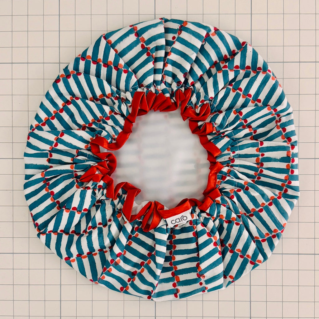 Striped fabric bath hat with red accents on a grid background