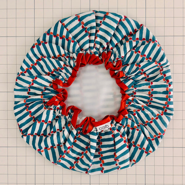 Striped fabric bath hat with red accents on a grid background