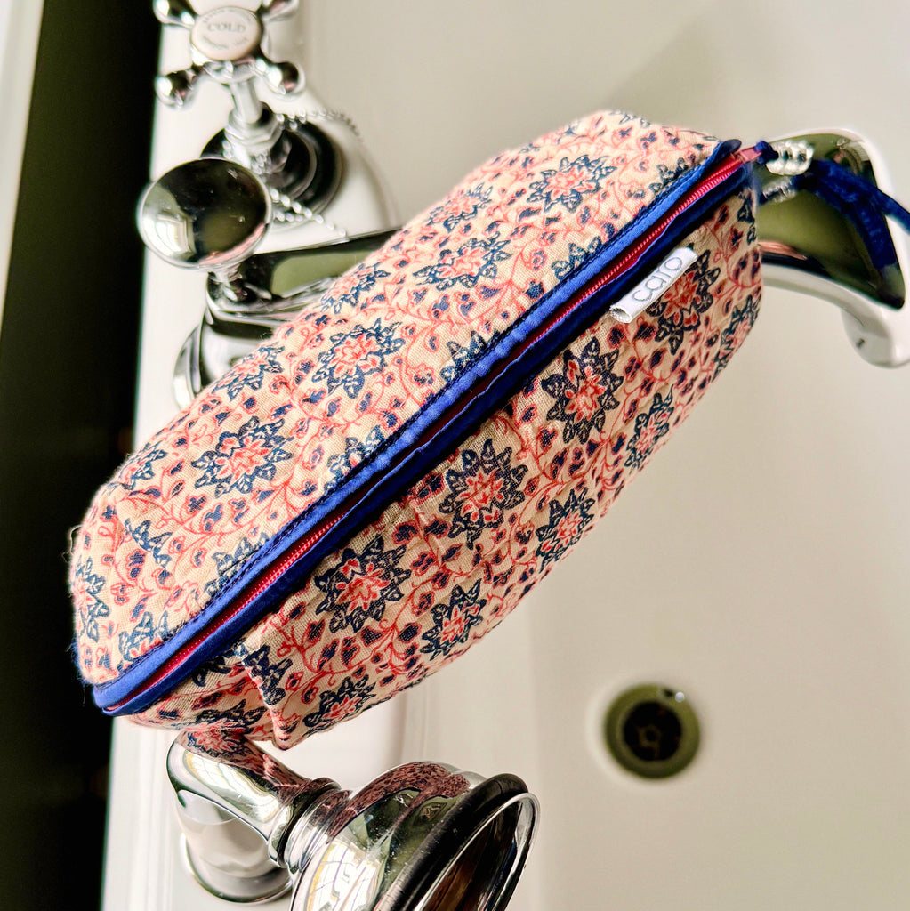 Over view of long, quilted make up bag in peach and blue floral print with dark blue trim