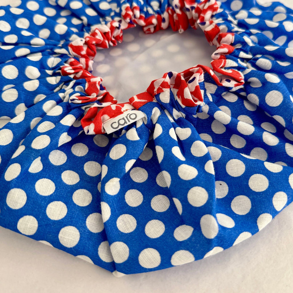 Close up of cotton bath hat in white 1cm wide spot on rich blue ground and orange floral binding trim