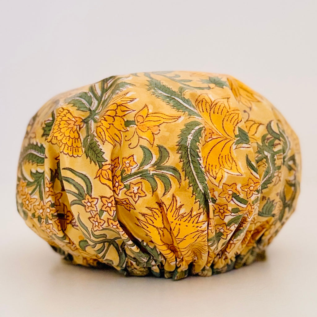 Shower Cap in vibrant yellow floral pattern with green leaves, displayed on a light-colored surface.