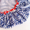 Close-up of a shower cap with a blue and white coral-like pattern, red elasticized edges, and a small visible 'caro' brand tag.
