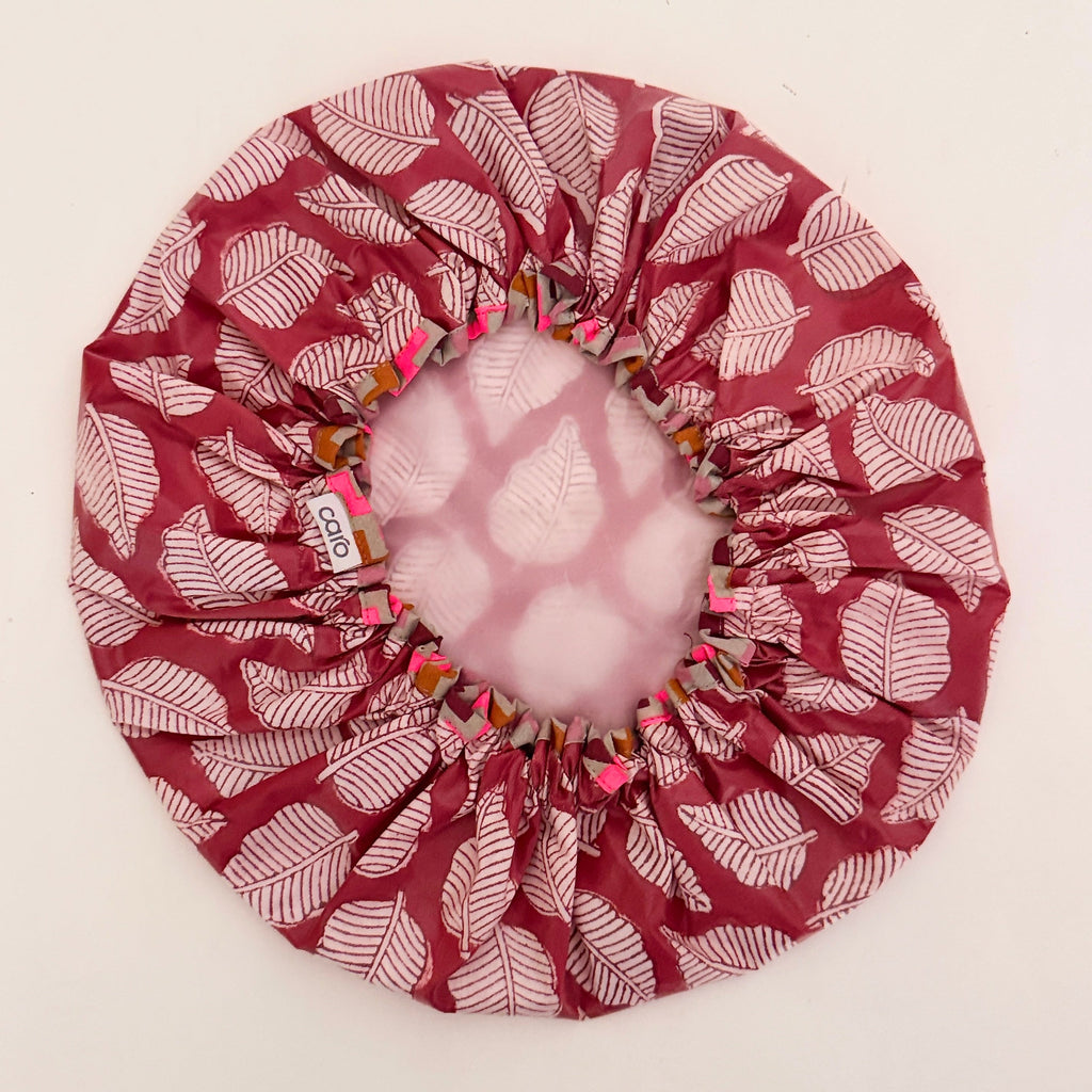 Photo of inside of a red leaf print shower cap with white water resistant lining