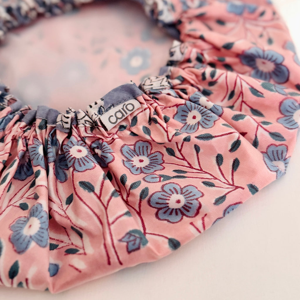 Close up of shower Cap in pretty pink and blue floral pattern displayed on a light-colored surface