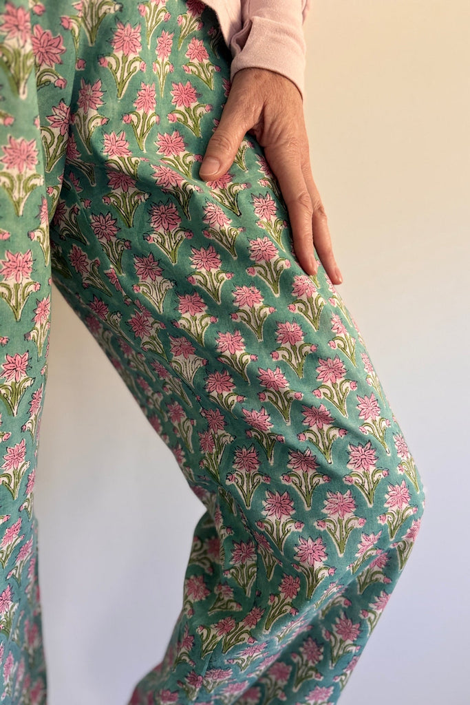 Floral patterned pants being worn on a plain background
