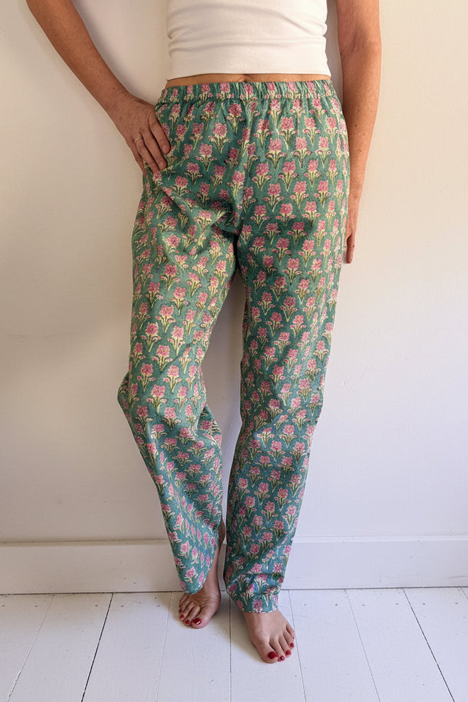 Person wearing blue and pink floral pyjama bottoms against white background.