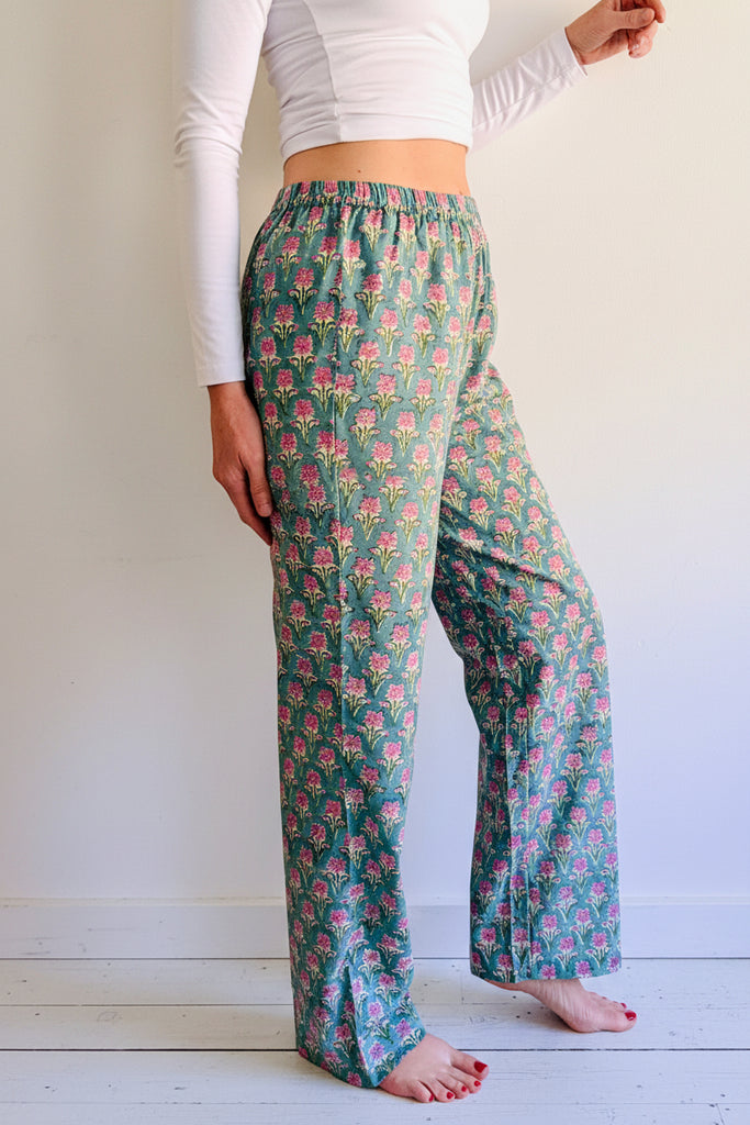 Person wearing floral pajama pants on a wooden platform with a white background