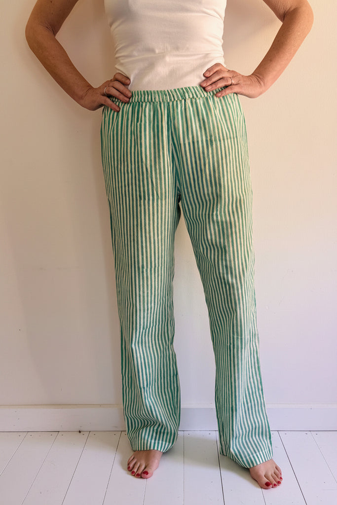 Person wearing green and white striped pants against a plain background