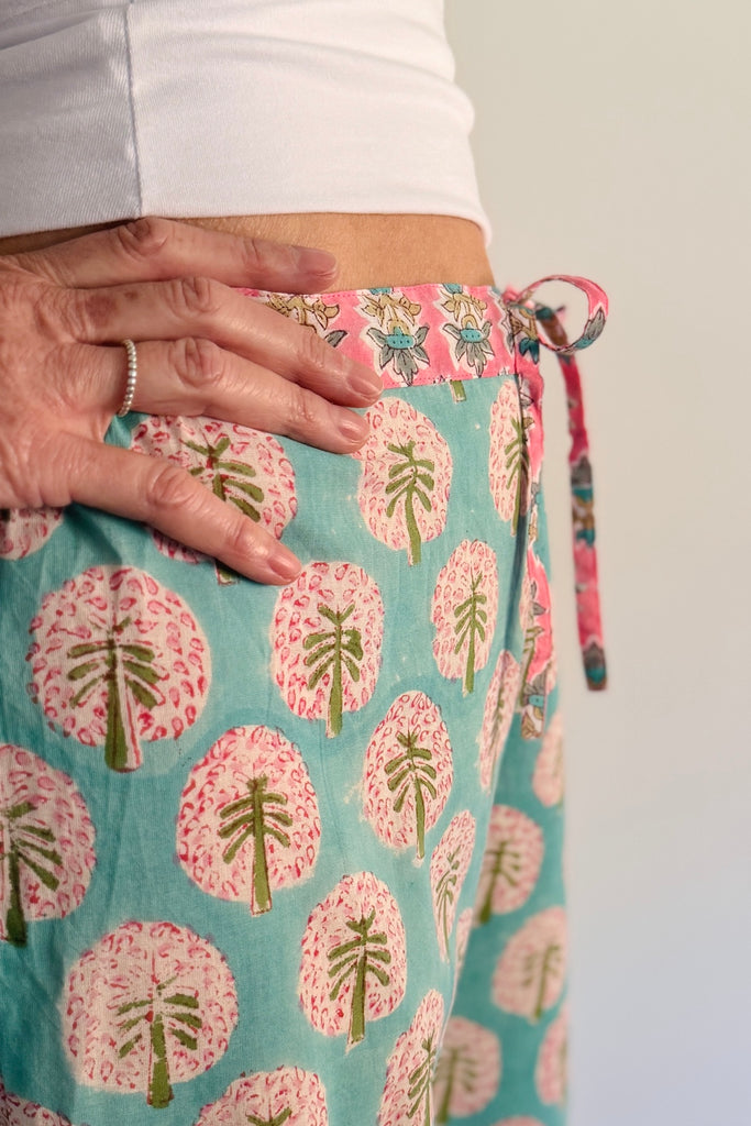Close-up of waistband of a person wearing a floral patterned pyjama bottom with a plain background