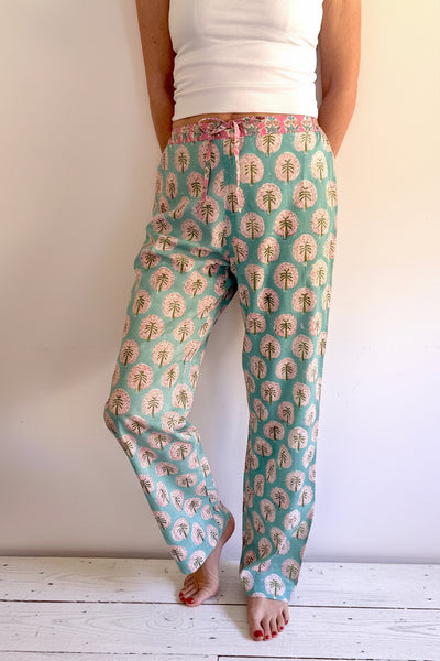 Person wearing teal pants with a floral pattern on a white background