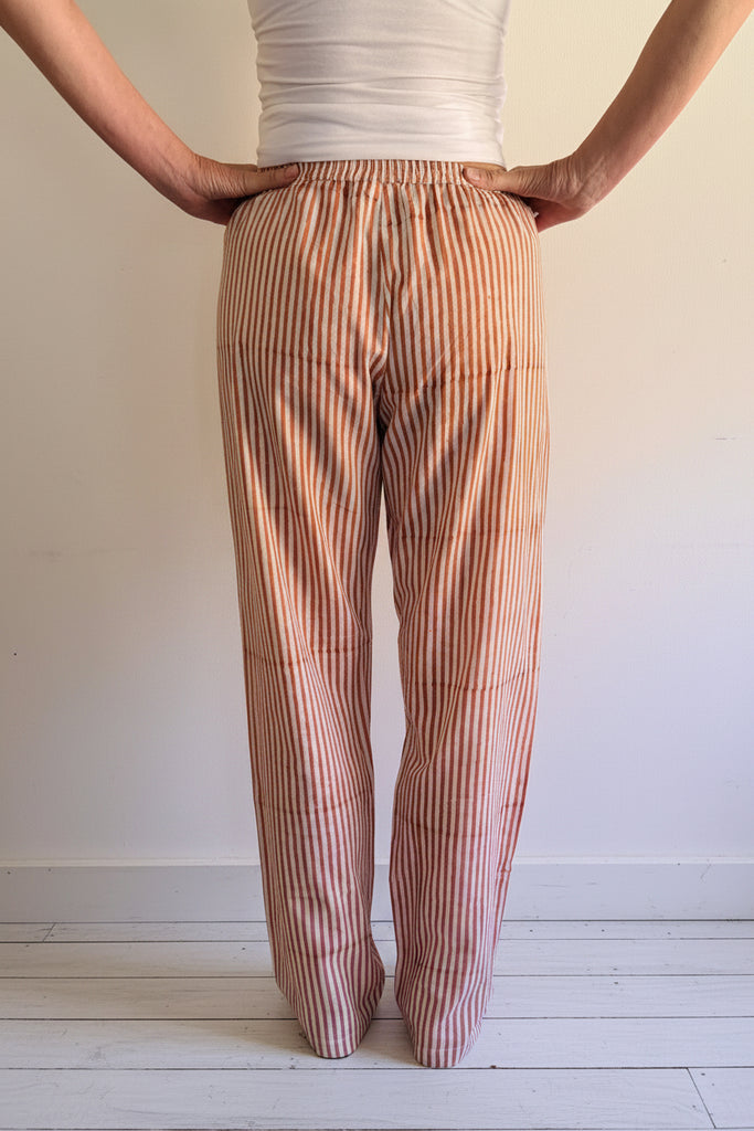 Person wearing light pink striped pants and a white top.