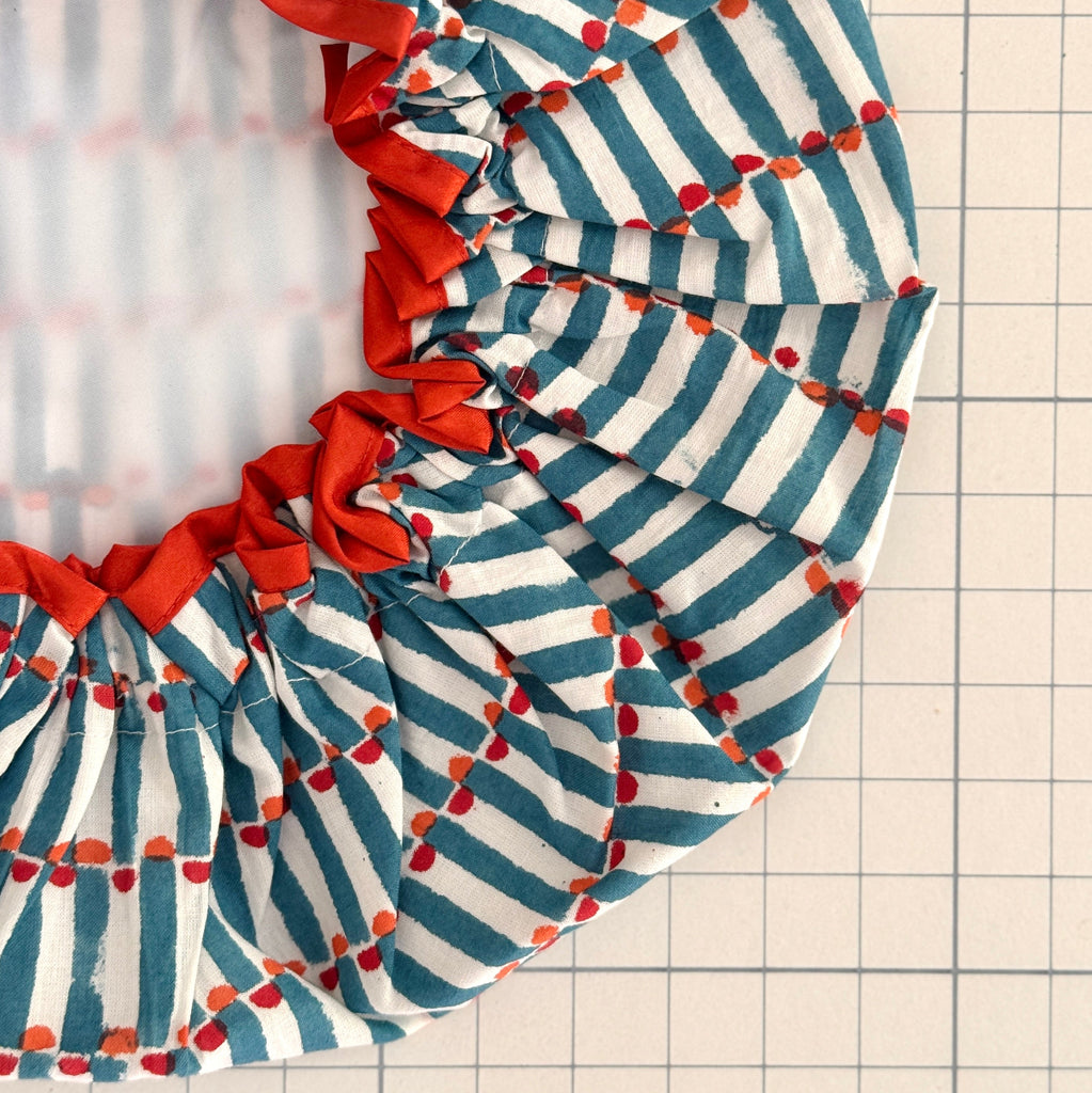 Close up of Dot and Dash geometric bath hat with orange trim and white water resistant lining