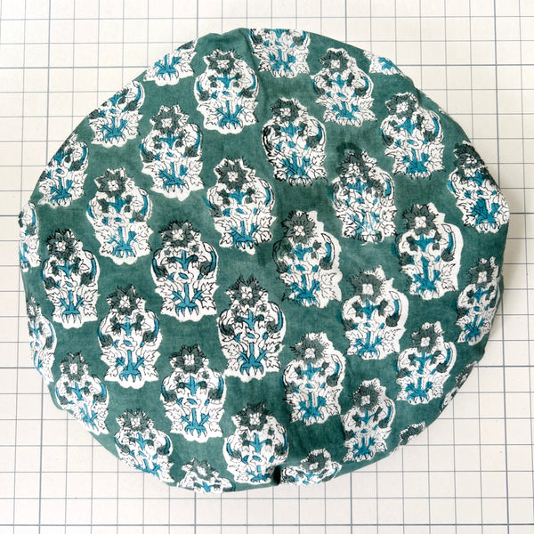 Cotton bath hat with water resistant lining. Green and white flowers on a sage green ground.