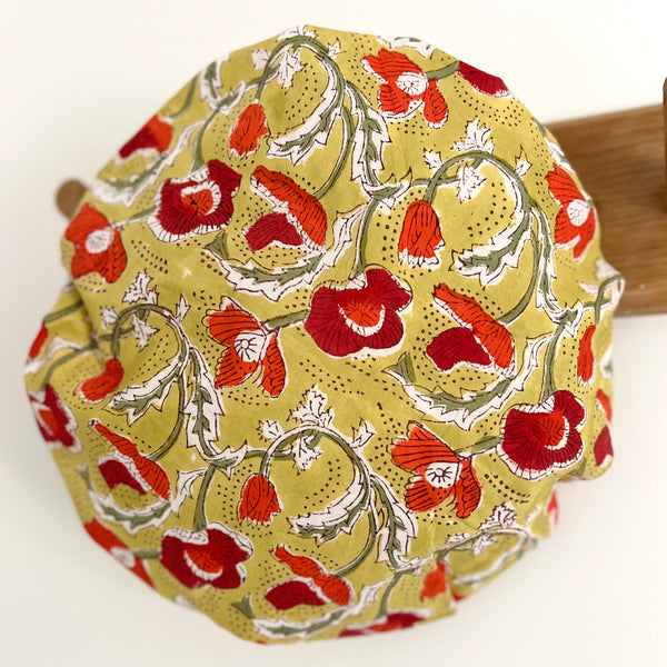 Cotton bath hat with water resistant lining. Made from red, white and green poppy print on dijon yellow ground and dotted highlights