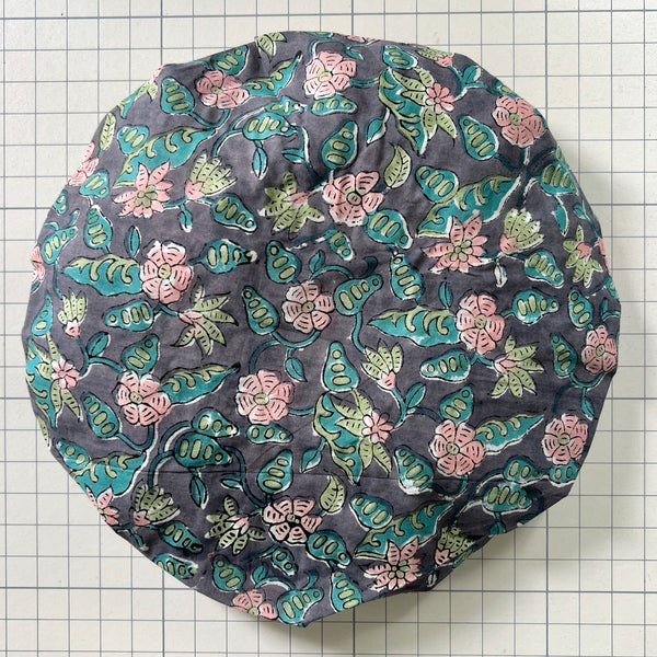 Cotton bath hat in light pink flowers on dark blue ground and green leaves. keeps your hair dry in the bath.