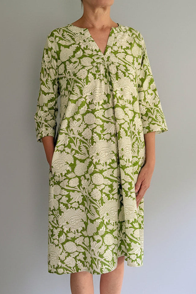 Person wearing a green floral dress against a plain background