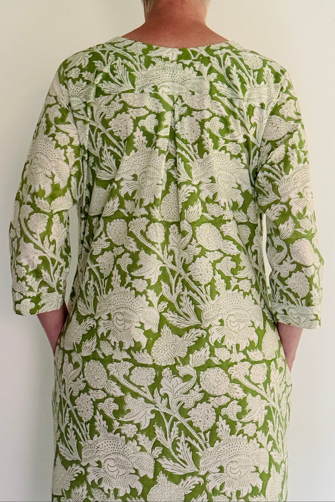 Person wearing a green and white patterned dress against a plain background