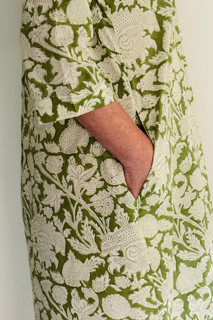 Green and white floral patterned fabric with a hand visible in the pocket.