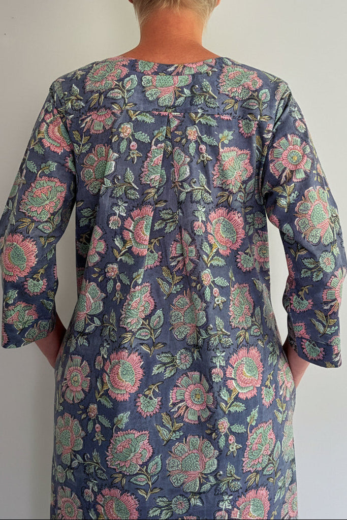 Person wearing a floral patterned dress against a plain background