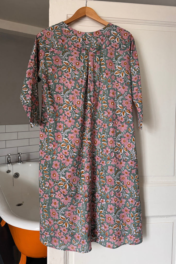 Floral nightdress hanging on a hanger against a bathroom wall.