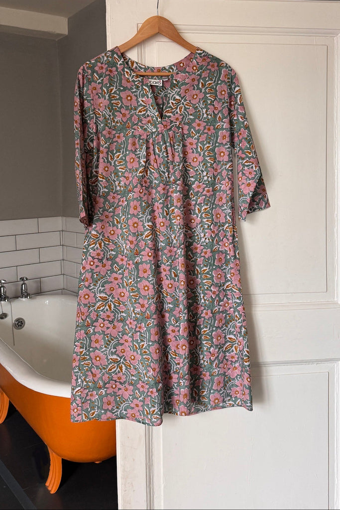 Floral kaftan nightdress hanging on a hanger against a white door with an orange bathtub in the background.