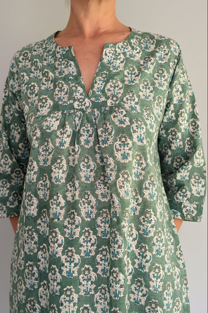 Green floral patterned dress worn by a person against a white background