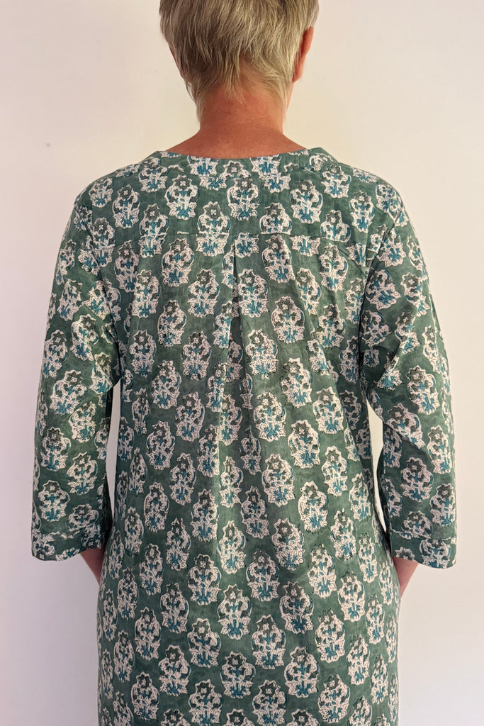 Person wearing a green floral patterned dress against a white background