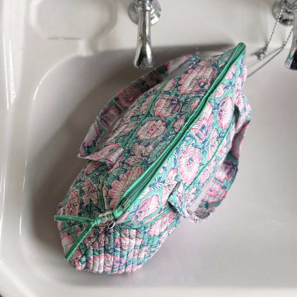 Turquoise and Pink floral washbag with handle on white basin