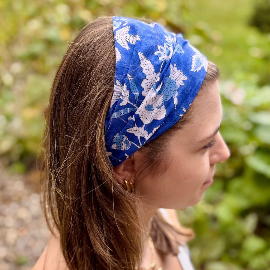 Woman wearing a blue floral headband with a blurred natural background