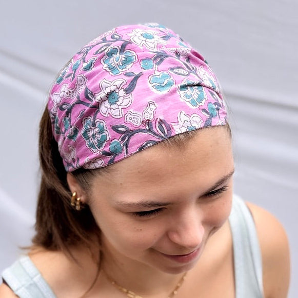 Woman wearing a pink floral headband against a plain background