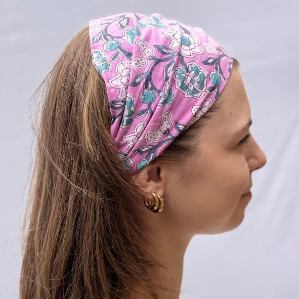 Woman wearing a pink floral headscarf against a plain background