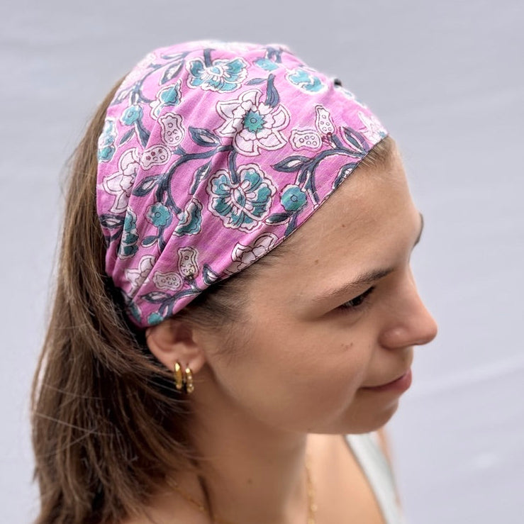Woman wearing a pink floral headband against a plain background