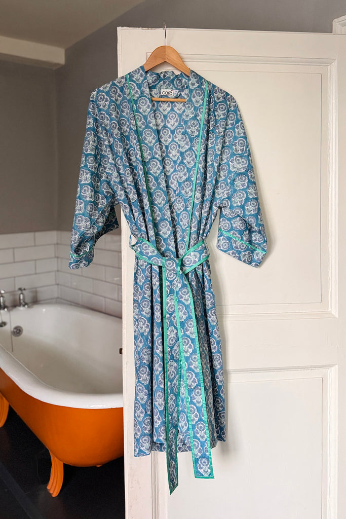 Blue patterned robe hanging on a door next to a bathtub.