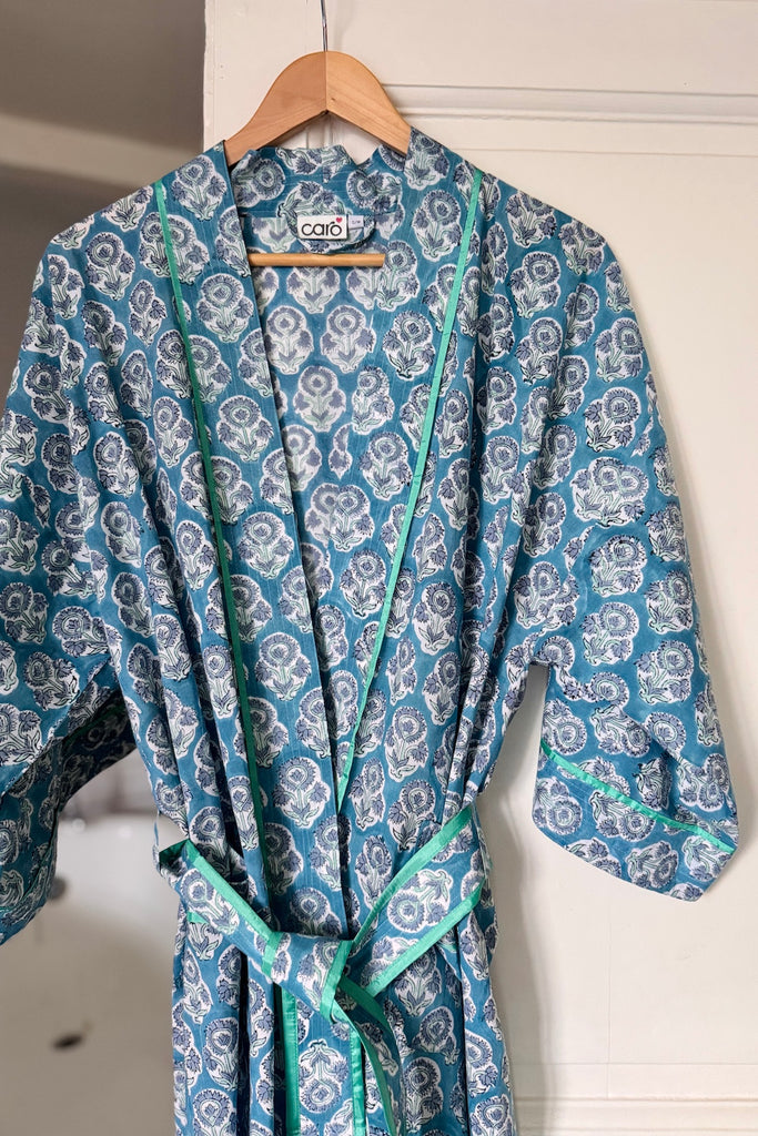 Blue floral-patterned robe on a hanger against a white wall