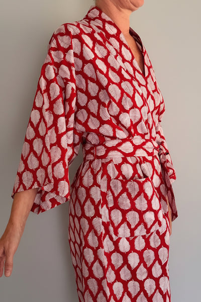 A woman wearing a red and white patterned wrap robe with three-quarter sleeves and a matching waist tie, shown against a plain light background.