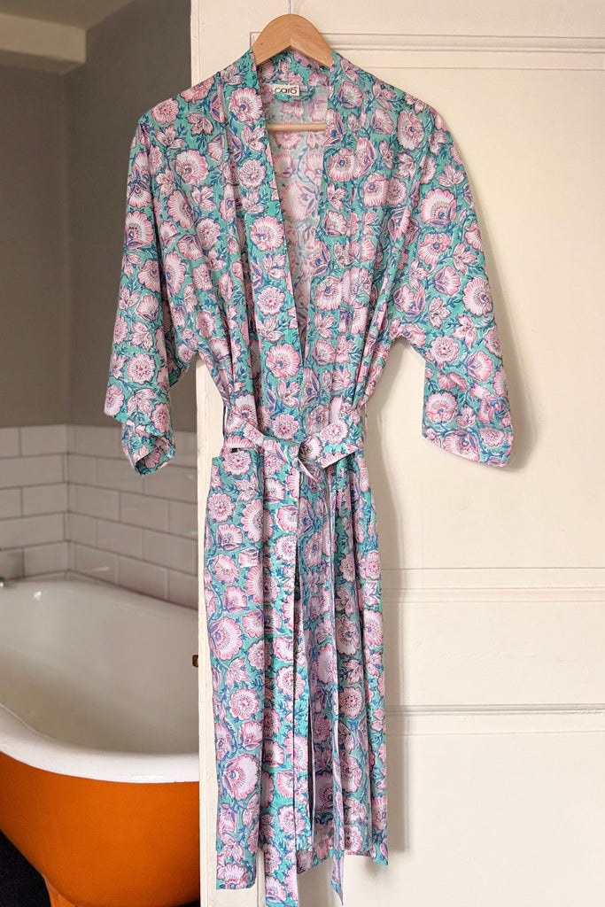 Floral patterned robe hanging in a bathroom with a bathtub.