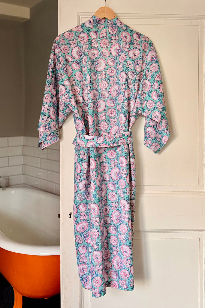 Floral robe hanging on a door in a bathroom with an orange bathtub.