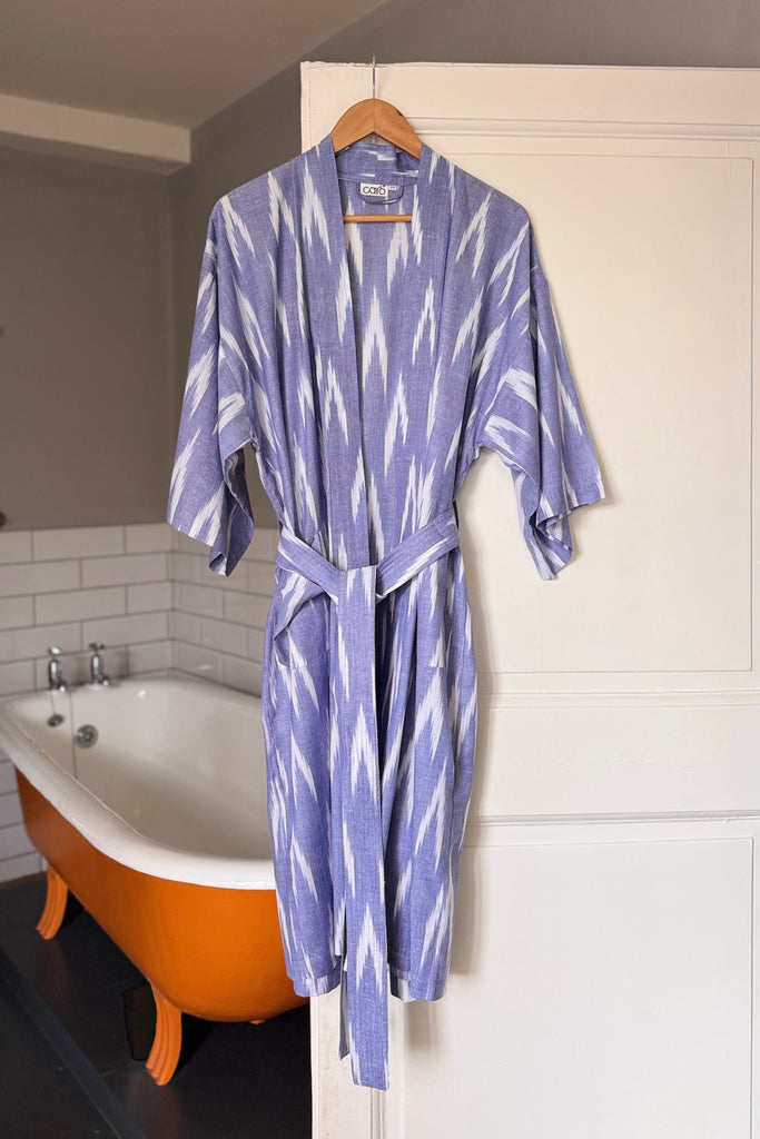 Purple and white patterned robe hanging on a hook in a bathroom.