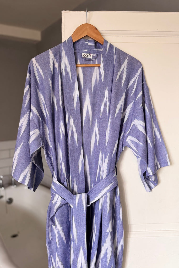 Blue and white patterned robe hanging on a wooden hanger against a white wall.